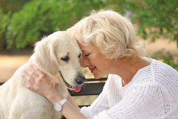 Senior woman sitting on bench with dog, closeup