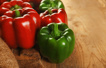 Sweet red and green peppers on wooden background, closeup