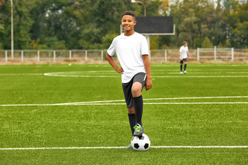 Obraz premium Boy playing football at stadium