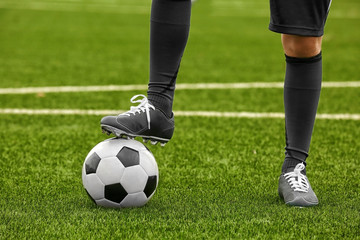Football player holding ball with foot, closeup