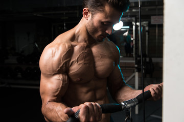 Fototapeta na wymiar Young Man Exercising Biceps In The Gym