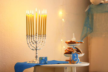 Menorah, dreidels and cookies for Hanukkah on stool in living room