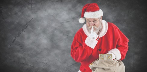 Composite image of santa claus with finger on lips and holding a
