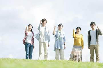 草原でガッツポーズをする若者たち