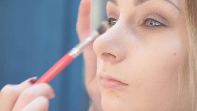 Visagist puts shadows on the eyelid, close up