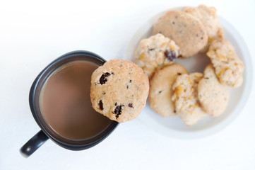 Butter cookies with raisins cornflakes and sesame served with a cup of coffee on white background.