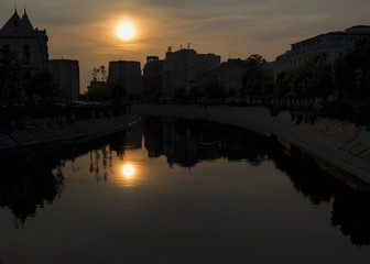 Fototapeta na wymiar Abstract city skyline. Sunset time view of city of Bucharest, reflected in Dambovita River.