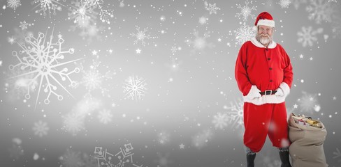 Composite image of santa claus standing with bag of gifts