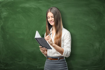 Young businesswoman holding her open day planner and going to write something