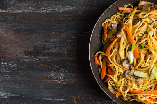 Delicious vegetarian pasta with vegetables and mushrooms on wooden table