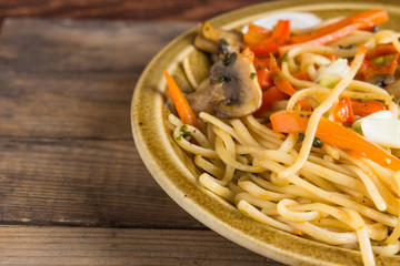 Delicious vegetarian pasta with vegetables and mushrooms on wooden table. Shallow depth of field.