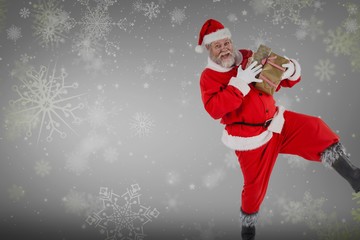 Composite image of portrait of playful santa claus holding prese