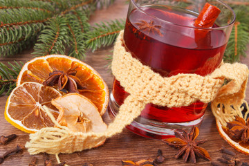 Glass of mulled wine wrapped scarf, spices and spruce branches