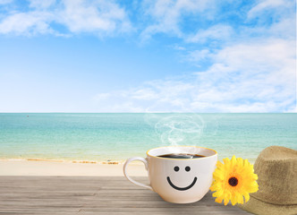 cup of coffee with happy face on sand beach over blue sky and sea. concept relax travel in holiday