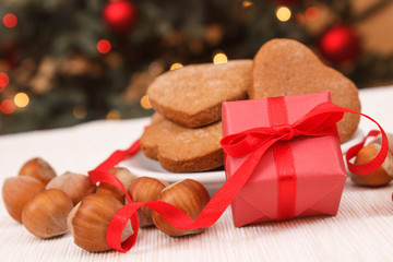 Wrapped gift, gingerbreads and christmas tree with lights in background