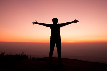 Fototapeta premium Girl opens arm with sunset sky background, inspiration and freedom concept