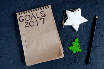 Fototapeta na wymiar notebook and goals for new year dark background top view