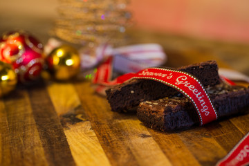 Lovely close up image of Christmas cookies on a wooden chopping board with some scented candles and a glass of whiskey / coffee and some cinnamon sticks.