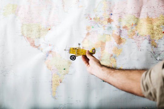 Man holding airplane in front of word map