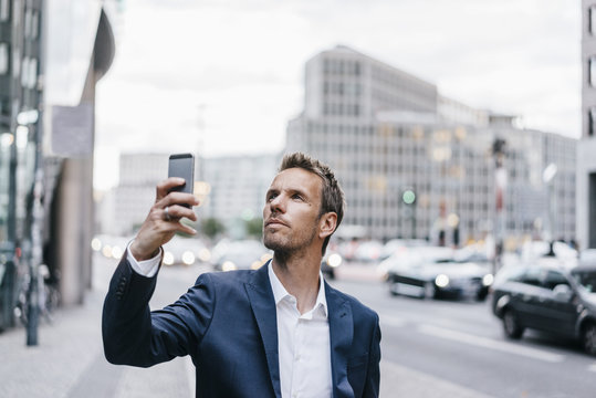 Businessman taking picture with smartphone