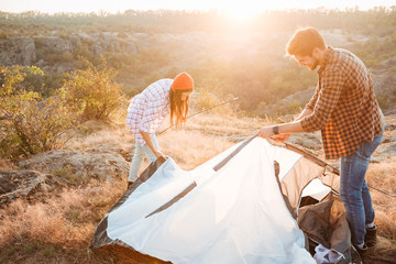 Young happy couple setting up a tent outdoors