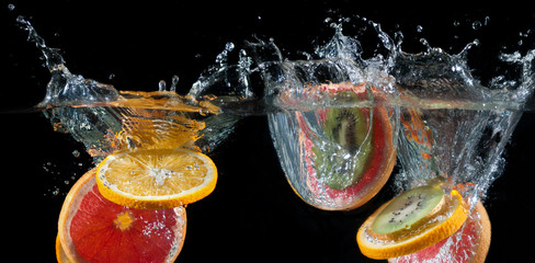 Fototapeta na wymiar Orange, lemon, grapefruit and lime splashing into water
