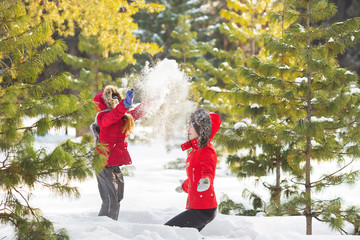 Mother and little daughter play with a snow in wood in winter