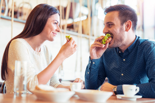 Beautiful young couple sitting in a cafe, having breakfast