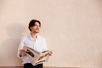 Confident young businessman reading newspaper
