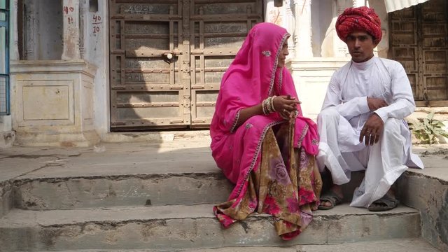 Indian couple in front of old Rajasthani architecture sitting and chatting 