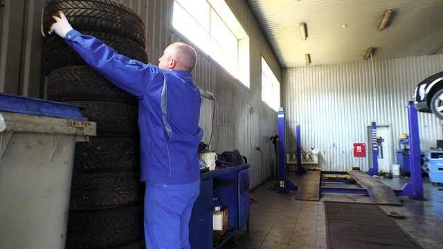 Man stacking worn tires in garage. tire changing and storing services.