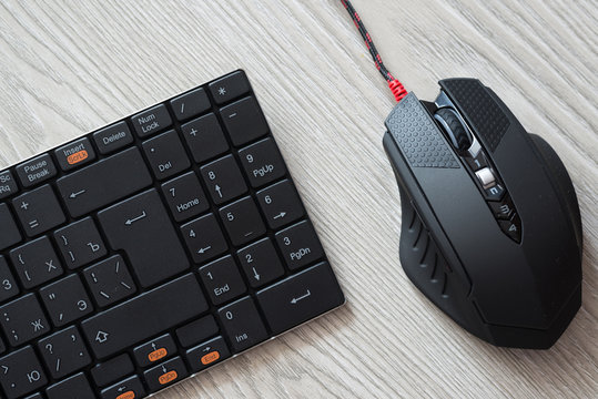 Top view of black computer mouse and keyboard with English and Russian letters