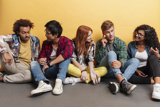 Multiethnic Group Of Smiling Young Friends Sitting And Talking