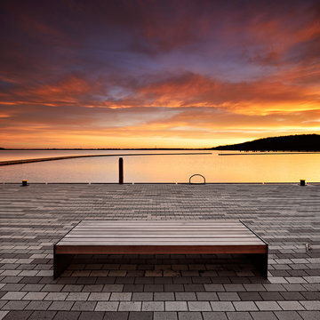 Sitzbank im Hafen bei Sonnenaufgang