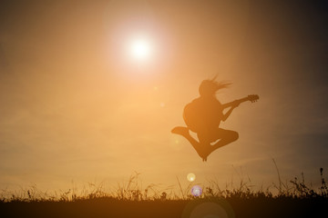 Silhouette happy girl playing guitar at the sky sunset, happy ti