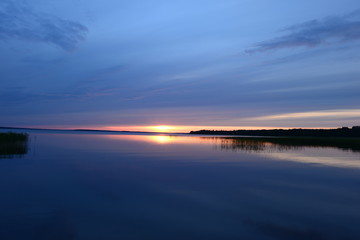 Fototapeta na wymiar Bright sunset on a blue azure water of the lake