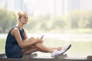 Happy woman listening music on line with headphones from a smart