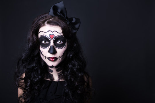 young woman with Halloween skull make up over black