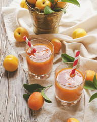 Fresh apricot juice in glass on wooden table, selective focus