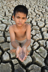  a boy drinking water on dry ground .concept drought