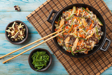 Rice noodles with chicken, mushrooms mun and vegetables in wook. © gkrphoto