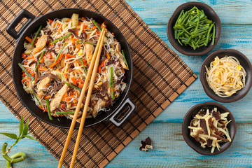 Rice noodles with chicken, mushrooms mun and vegetables in wook.