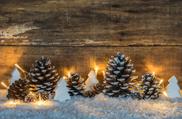 Weihnachtsdekoration rustikal mit Zapfen und Weihnachtsbäume aus Holz weiß im Schnee