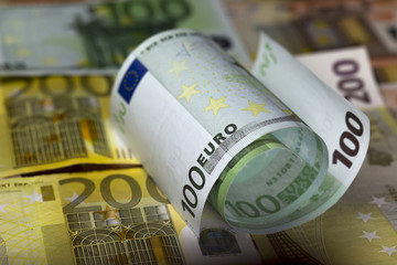 Two  half rolled hundred euro banknotes lying on euro 200 banknotes background
