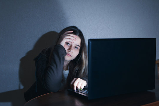 sad and scared female teenager with tablet computer and laptop suffering cyberbullying and harassment being online abused by stalker or gossip feeling desperate and humiliated