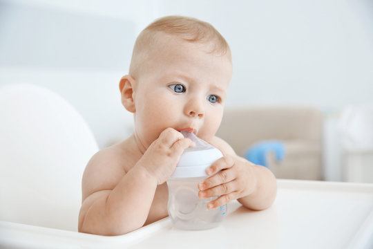 Little Baby Drinking Water From Bottle Indoors