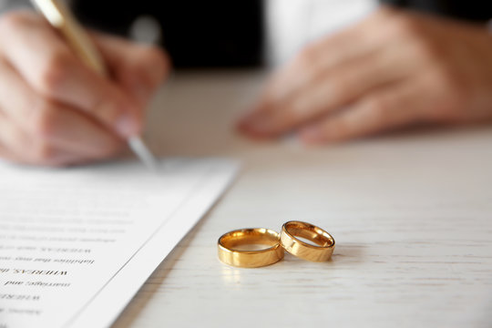 Golden wedding rings on table at notary office, closeup
