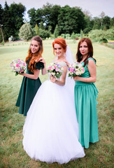 Fototapeta na wymiar happy and young bride and her bridesmaids standing outdoors