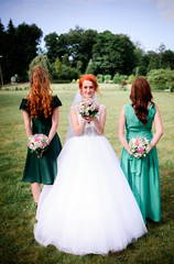 Fototapeta na wymiar happy and young bride and her bridesmaids standing outdoors