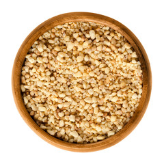Hazelnut brittle in wooden bowl, also called croquant. Brown confection of broken hard caramelized sugar candy embedded with nuts. Isolated macro food photo close up from above on white background.